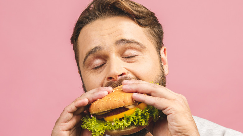 a bearded man bites into a burger