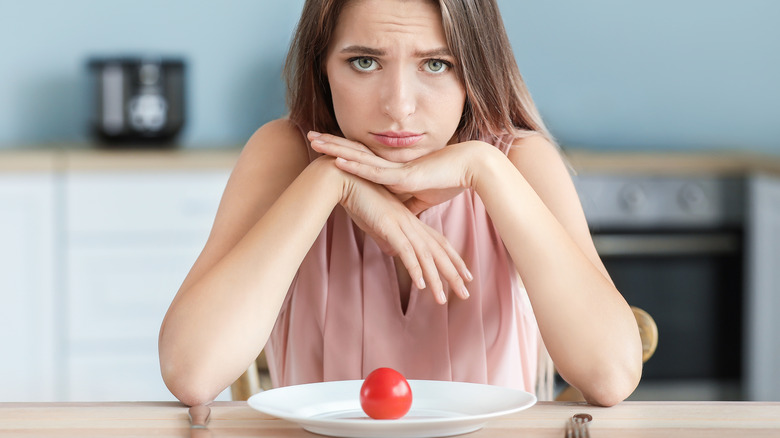 woman with a single tomato on plate