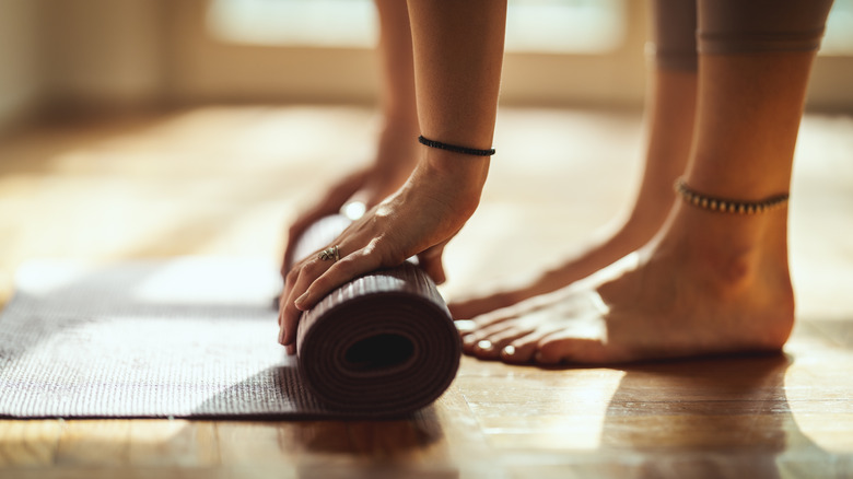 woman rolling up yoga mat
