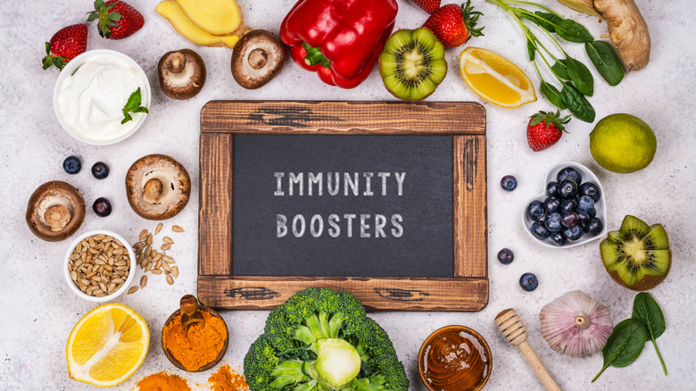 Variety of fruits, vegetables, nuts, and herbs around a sign that says "Immunity Boosters"