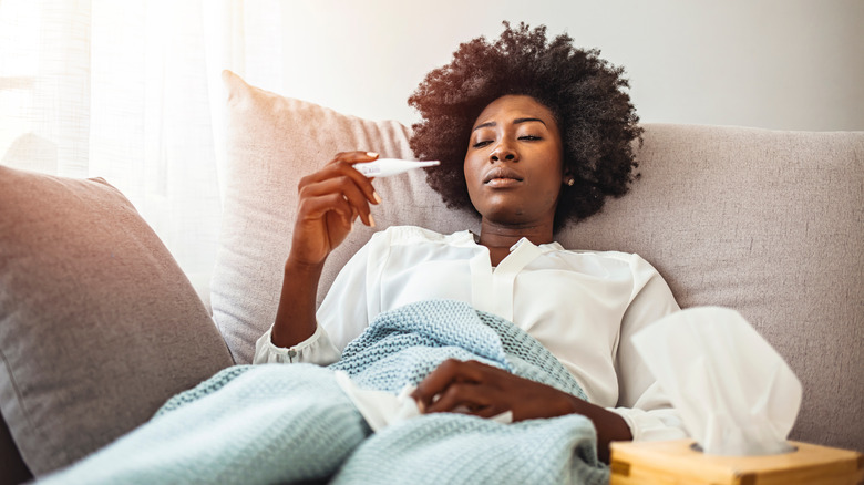 Woman in bed checking her temperature