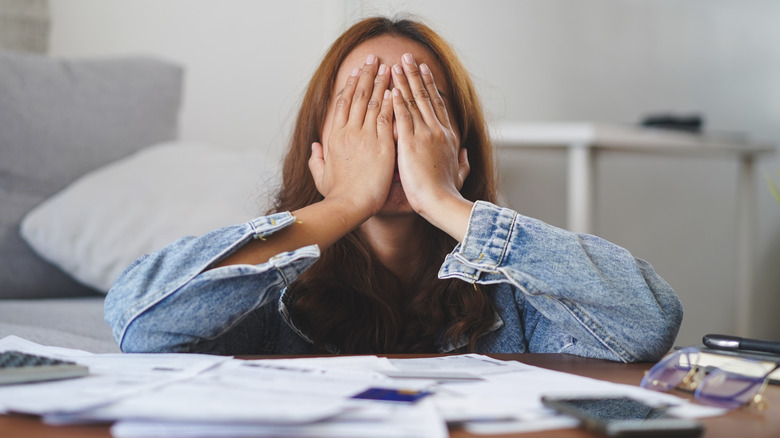 Woman with her head in her hands surrounded by bills