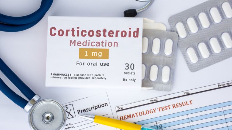 Box of corticosteroid pills on a table with medical paperwork and a stethoscope