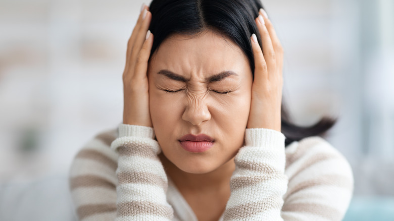 woman covers ears because the noise is too loud