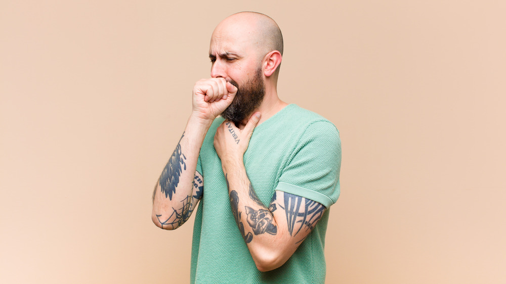 tattooed man coughing