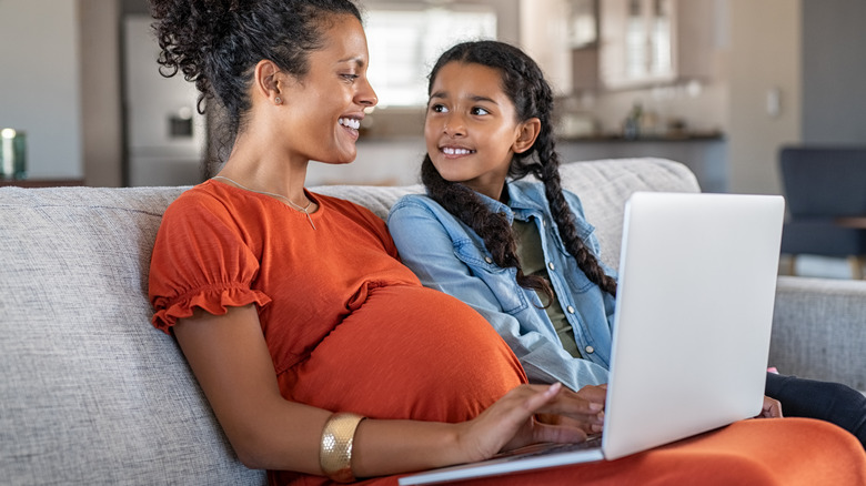 Pregnant woman with laptop with young daughter