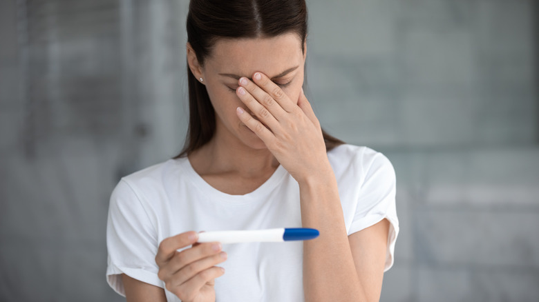 Disappointed woman holding a pregnancy test