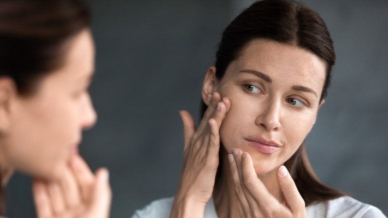 Woman with BDD examining her face in a mirror