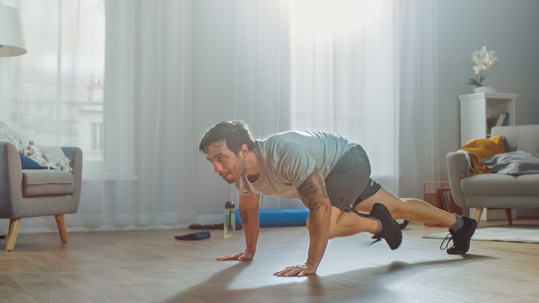 man doing muscle climber exercises in his home