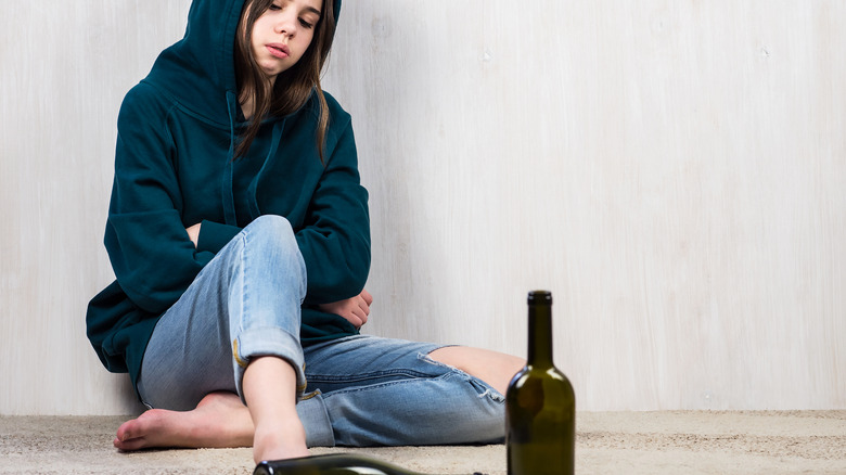 young girl with empty wine bottles