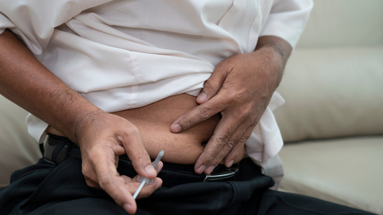 Black man doing a self-injection in his stomach