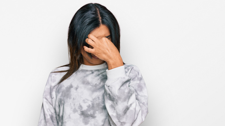 trans woman holding her head, headache