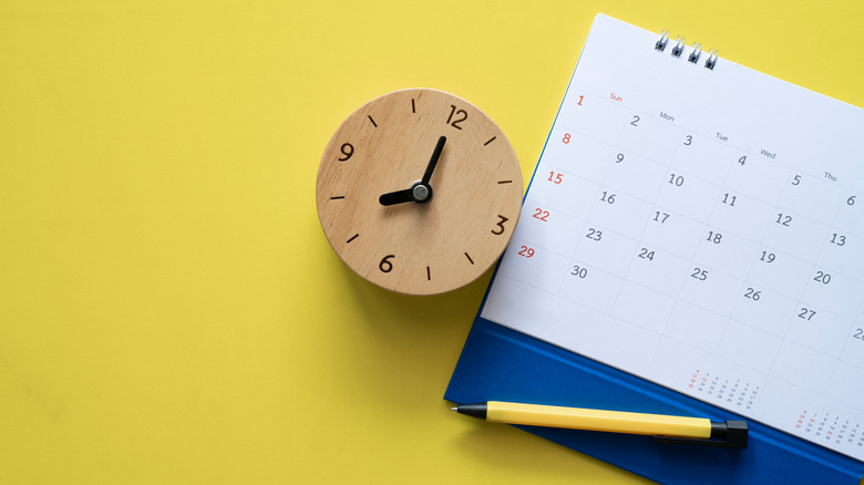 wooden clock by schedule planner on yellow background