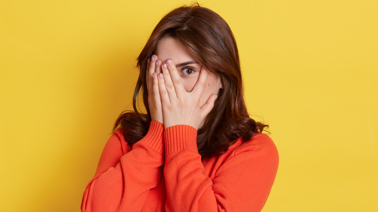 apprehensive woman peeking out from her hands