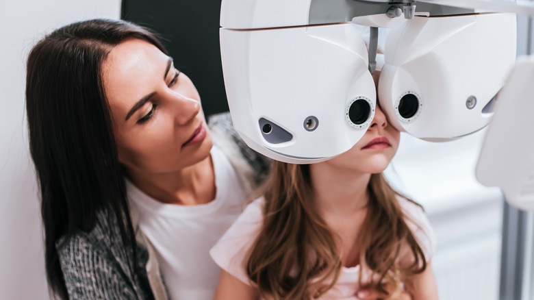 Woman holding little girl during eye exam