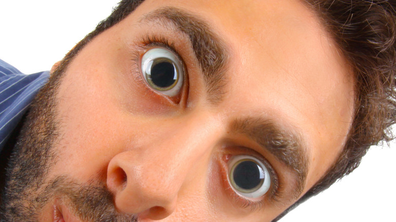 Young man with huge dilated eyes looking surprised