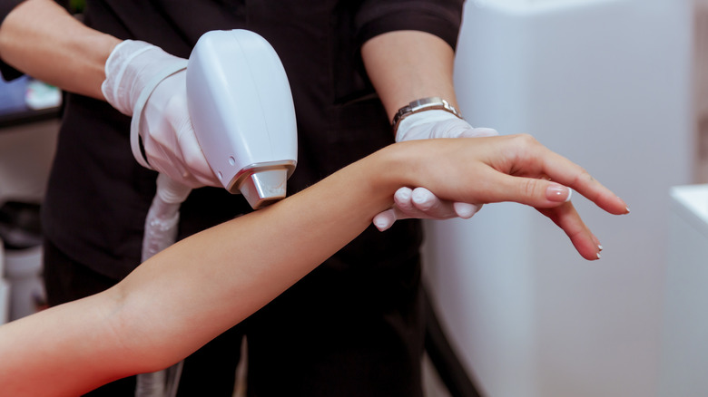 man performing laser hair removal on woman's arm