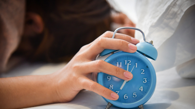 woman lying down with an alarm clock in her hand