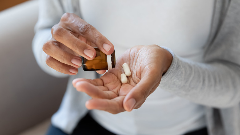 woman taking capsules from a container