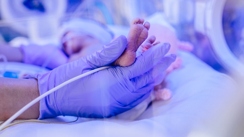 Doctor's gloved hand holding baby's foot