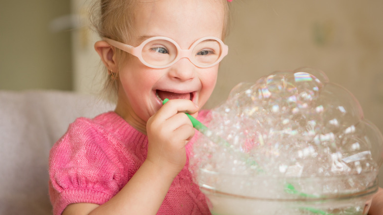 girl with Down syndrome blowing bubbles