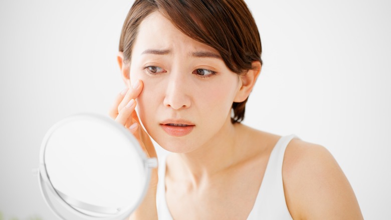 Woman looking at herself in the mirror with concern