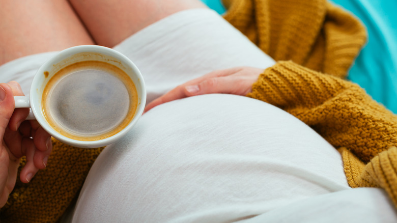 pregnant woman holding coffee mug