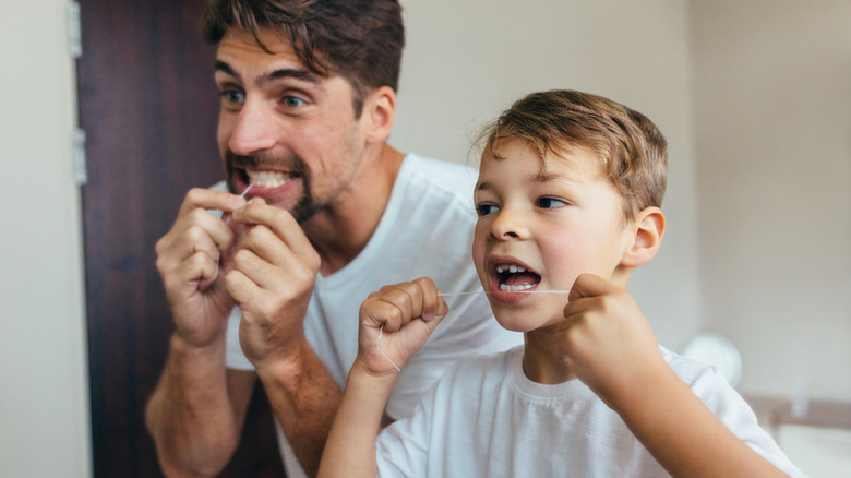 Father and son flossing teeth