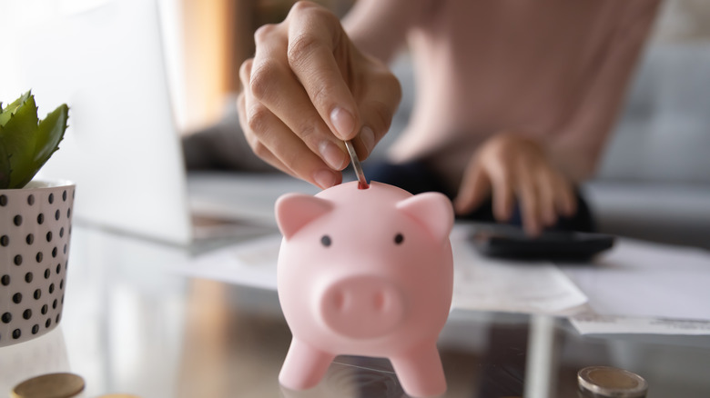 woman putting coins in piggy bank