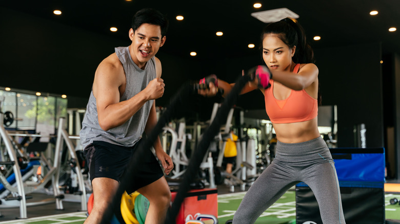 fit girl and trainer battle ropes