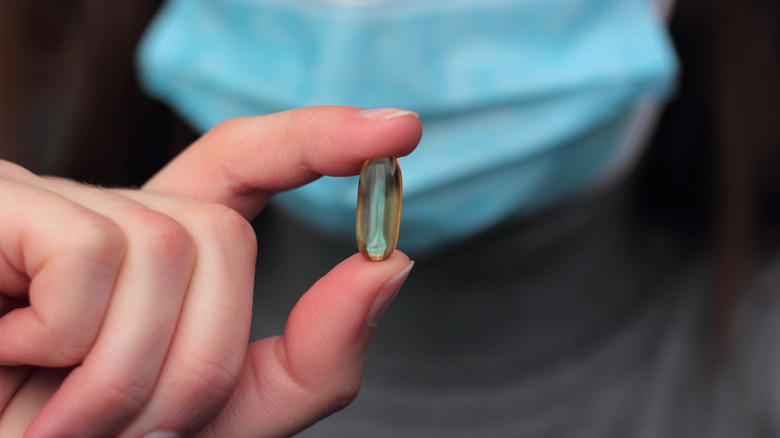 masked person holding a capsule