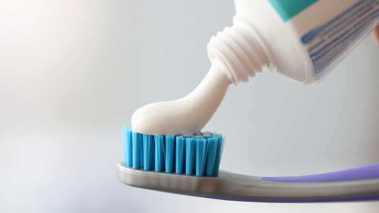 toothpaste being applied to toothbrush