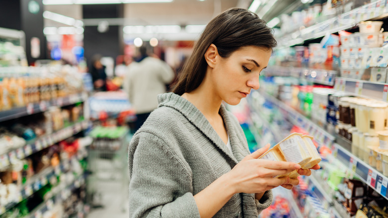 woman reading food label in grocery store