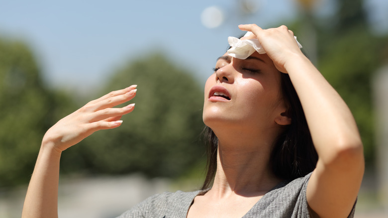 Woman sweating with towel on forehead