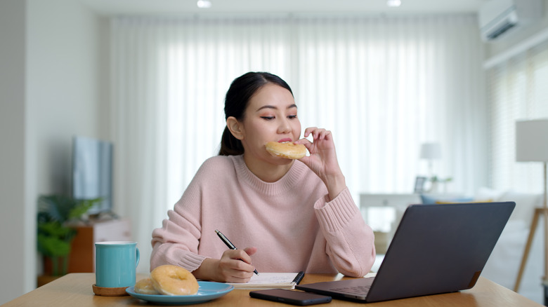 Woman at desk eating donut