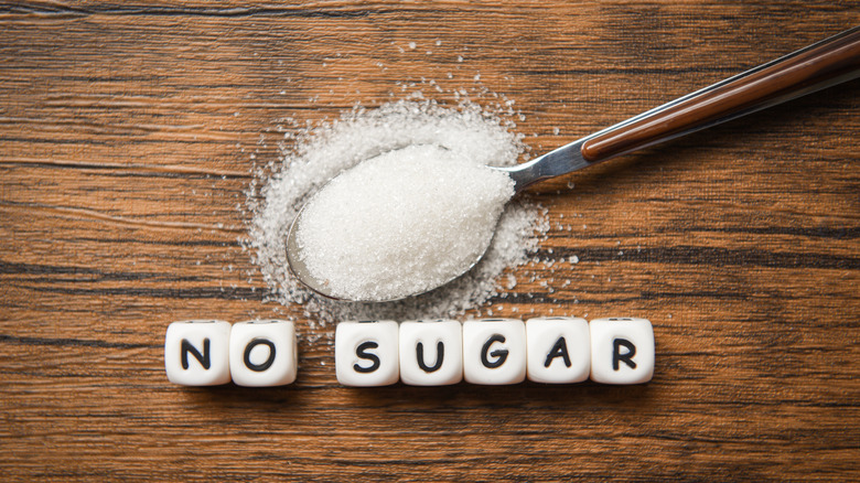 Block beads that spell out "no sugar" under an overflowing spoon of sugar