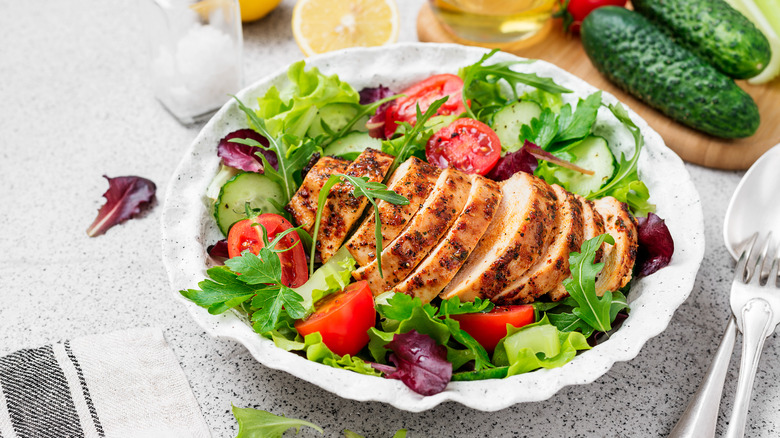 Green salad and tomatoes with sliced chicken