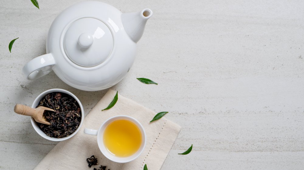 A cup of green tea with tea leaves and a tea pot (antioxidant)