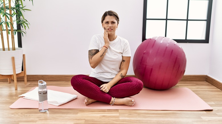 woman on yoga mat holding jaw