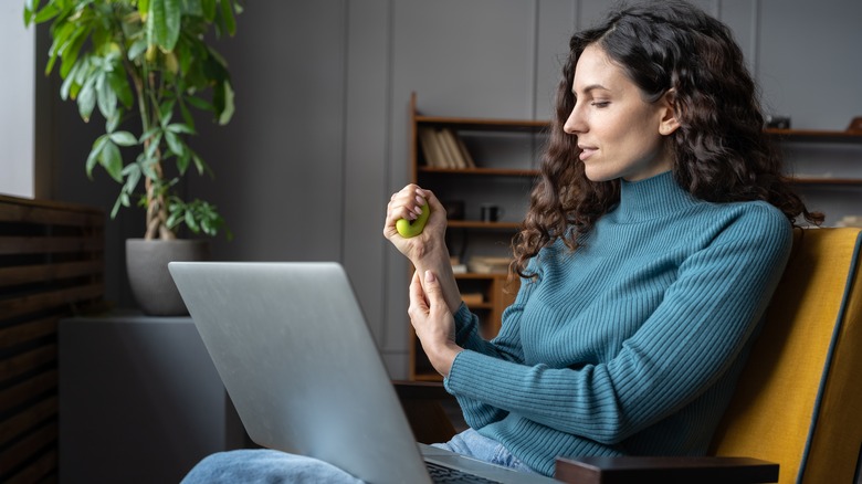 a woman uses a stress ball while sitting at her laptop