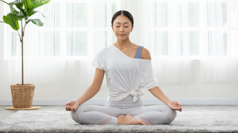 a woman seated doing yoga at home in meditation