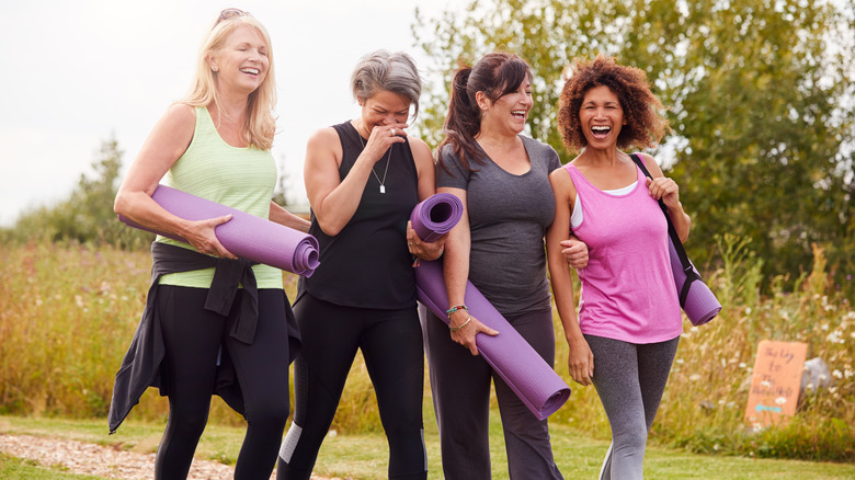 Laughing women carrying exerecise mats