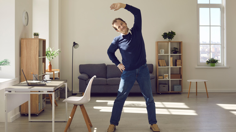 Man does standing stretches at his desk