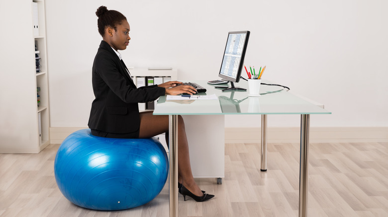 Black businesswoman uses exercise ball