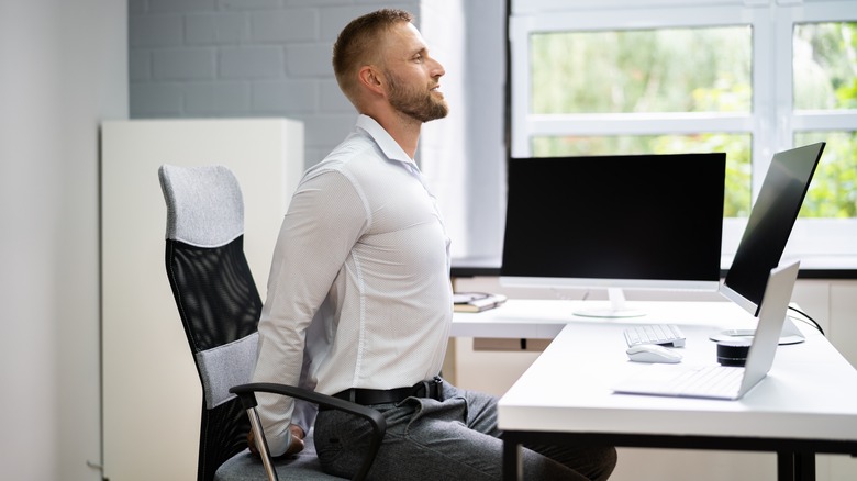 Light skinned man exercising at his desk