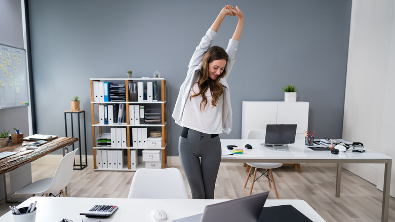 woman standing and stretching at her desk