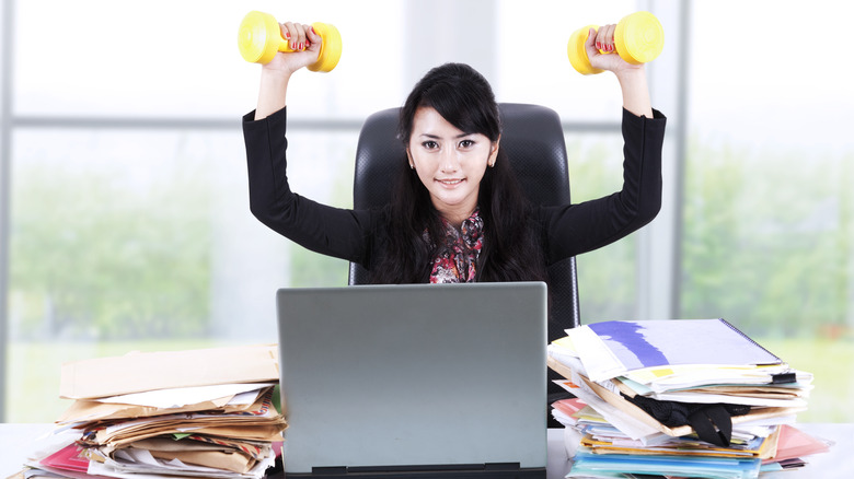 woman lifting dumbbells at her desk