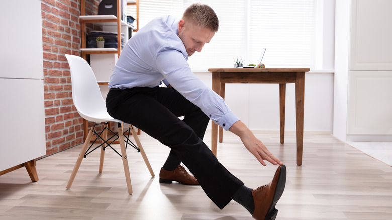Man doing a hamstring stretch at his desk