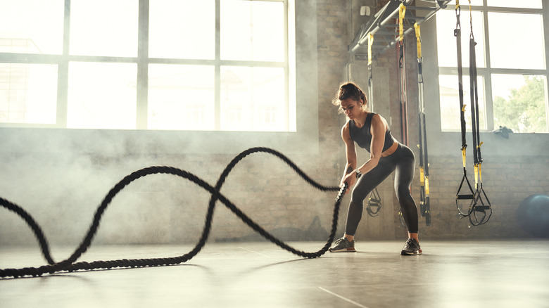 crossfit girl with battle ropes and trx