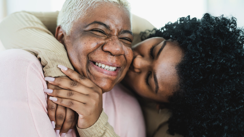 adult daughter kissing mother's cheek